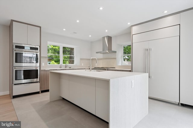 160 Union Ave, Bala Cynwyd, PA 19004 - kitchen with wall chimney exhaust hood, double oven, modern cabinets, a sink, and backsplash