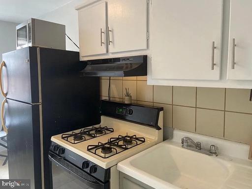 6631 Erdrick St, Philadelphia, PA 19135 - kitchen with gas range gas stove, under cabinet range hood, decorative backsplash, and white cabinets