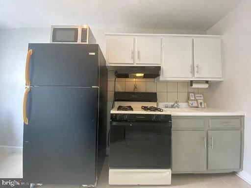 6631 Erdrick St, Philadelphia, PA 19135 - kitchen with white range with gas cooktop, freestanding refrigerator, under cabinet range hood, stainless steel microwave, and white cabinetry