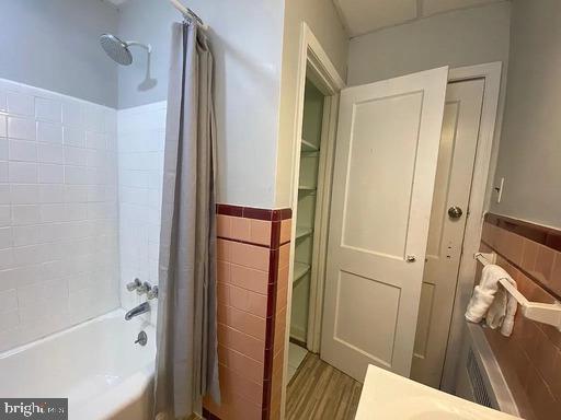 6631 Erdrick St, Philadelphia, PA 19135 - full bathroom featuring tile walls, wainscoting, shower / bath combo, and wood finished floors