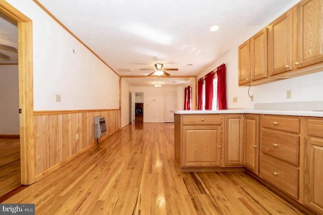 kitchen with ceiling fan, light wood-style floors, a wainscoted wall, light countertops, and a peninsula