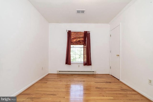 empty room with a baseboard radiator, light wood-type flooring, and baseboards