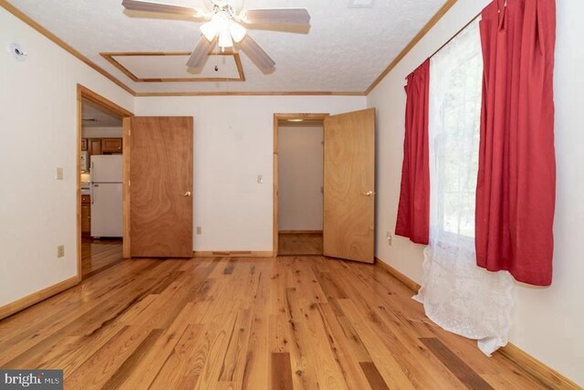 empty room with crown molding, wood finished floors, ceiling fan, and baseboards