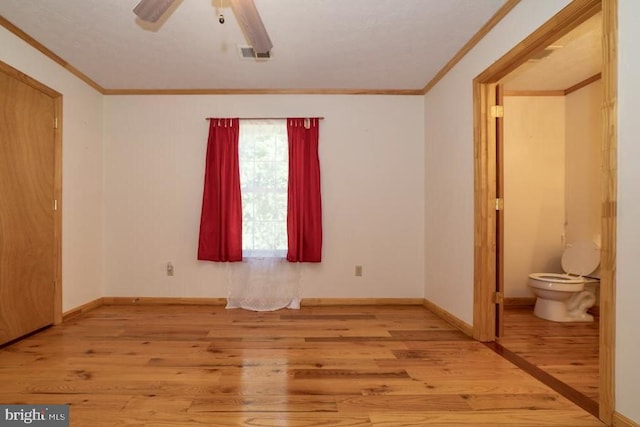 unfurnished bedroom featuring light wood-style floors, crown molding, baseboards, and a ceiling fan