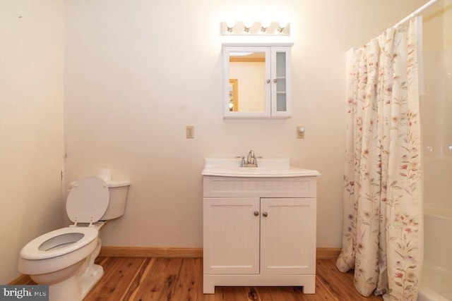 full bath featuring wood finished floors, baseboards, vanity, and toilet