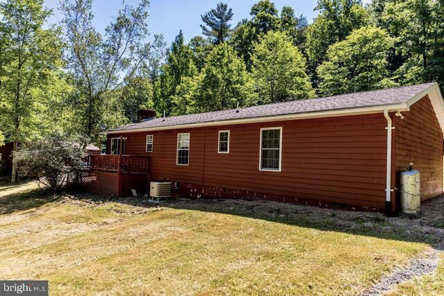 view of side of property featuring central AC unit, a deck, crawl space, a lawn, and a chimney