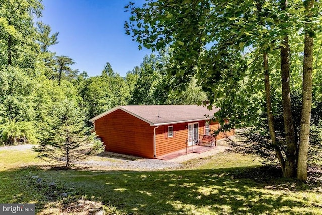 view of side of property with a yard, french doors, and a forest view