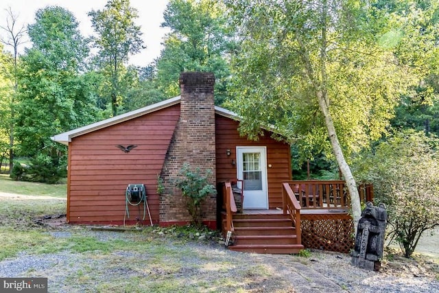 back of property with a wooden deck and a chimney