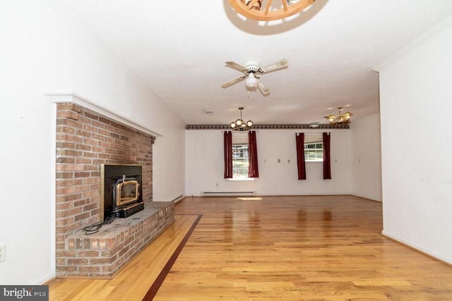 unfurnished living room with a chandelier, a baseboard radiator, light wood finished floors, and a wood stove