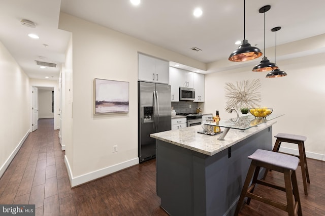 kitchen with stainless steel appliances, a kitchen bar, white cabinets, baseboards, and recessed lighting