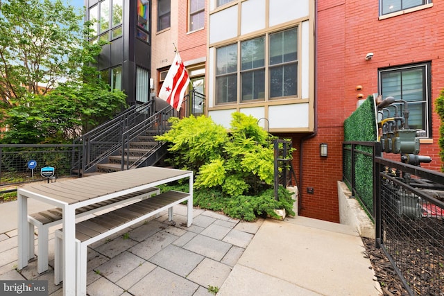 view of property's community with fence, a patio area, and stairway