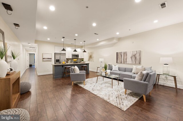 living area with baseboards, dark wood-type flooring, and recessed lighting