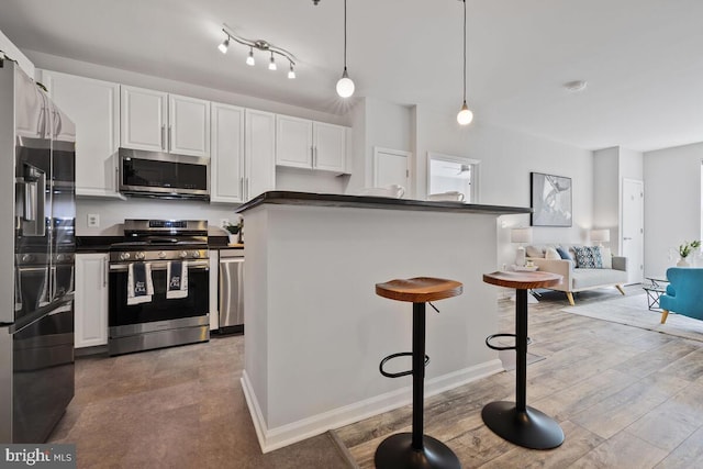 1201 E E W Hwy Unit 208, Silver Spring, MD 20910 - kitchen with stainless steel appliances, dark countertops, white cabinetry, a kitchen breakfast bar, and decorative light fixtures