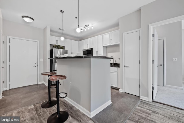 1201 E E W Hwy Unit 208, Silver Spring, MD 20910 - kitchen featuring wood finished floors, dark countertops, white cabinets, stainless steel appliances, and a kitchen island