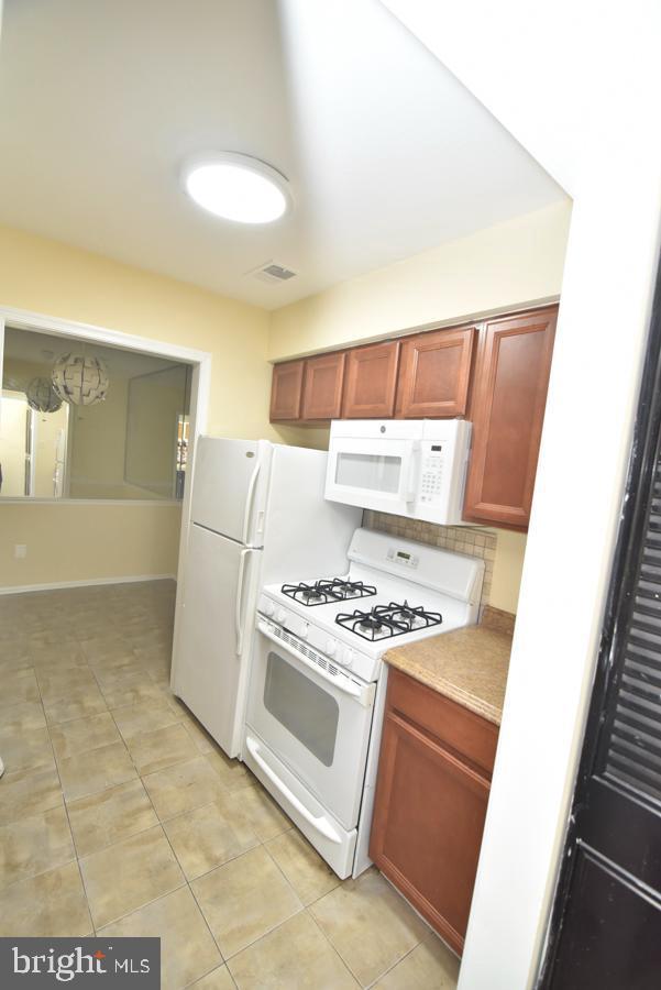3171 Chester Grove Rd, Upper Marlboro, MD 20774 - kitchen with white appliances, light tile patterned floors, and light countertops