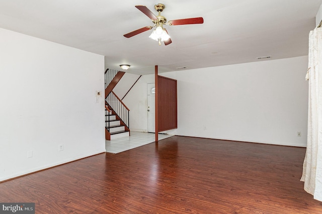 unfurnished living room with stairs, ceiling fan, and wood finished floors