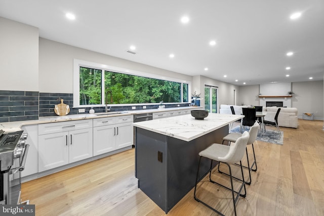 18 Haskel Dr, West Windsor, NJ 08550 - kitchen featuring appliances with stainless steel finishes, a kitchen island, light stone counters, white cabinets, and a glass covered fireplace