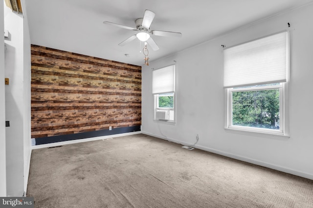 unfurnished room with wood walls, baseboards, carpet, and a ceiling fan