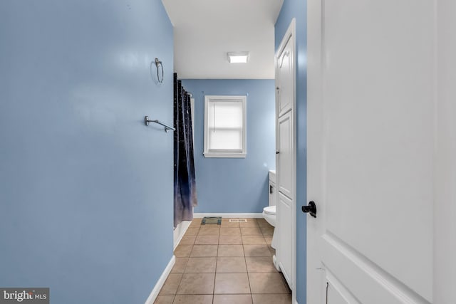 corridor with light tile patterned floors and baseboards