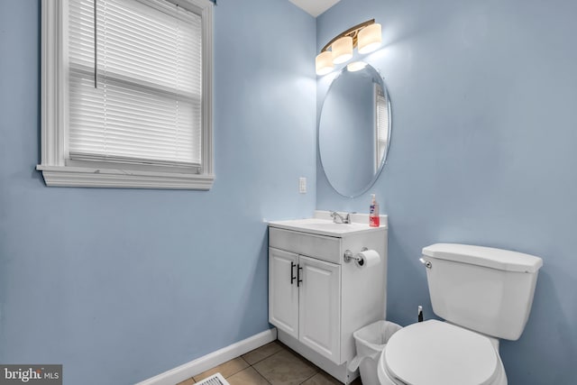 half bathroom with tile patterned flooring, toilet, vanity, and baseboards