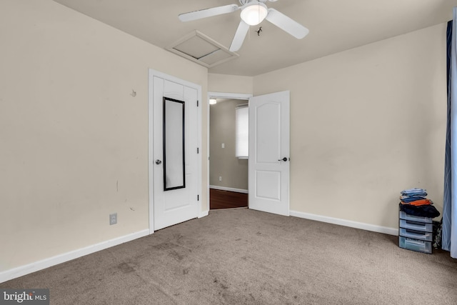 unfurnished bedroom featuring carpet flooring, attic access, baseboards, and ceiling fan