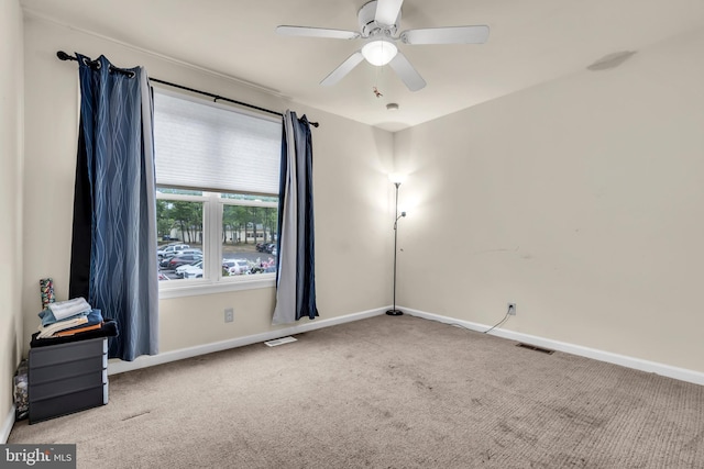 carpeted empty room featuring baseboards and a ceiling fan