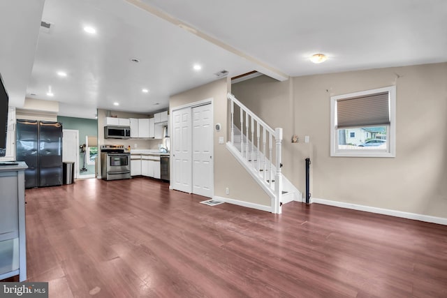 unfurnished living room featuring stairway, dark wood-style floors, baseboards, and recessed lighting