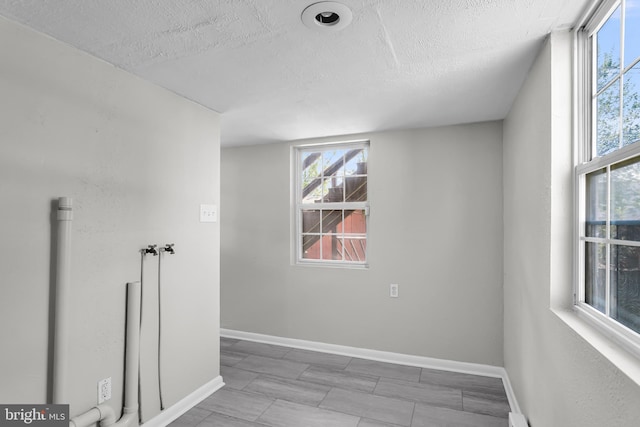 empty room with a textured ceiling and baseboards