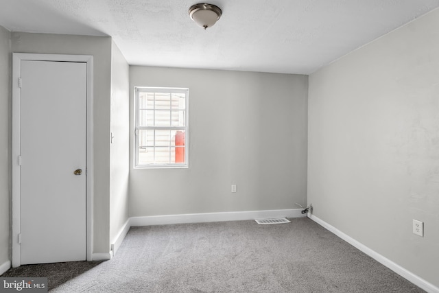 unfurnished bedroom with carpet flooring, baseboards, and a textured ceiling