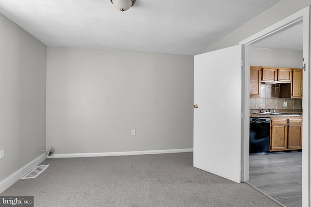 empty room featuring light carpet, baseboards, and a sink