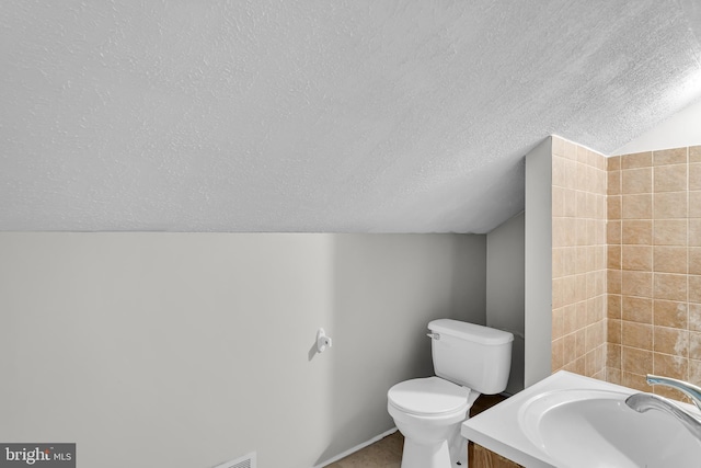 bathroom with a textured ceiling, toilet, vanity, baseboards, and lofted ceiling