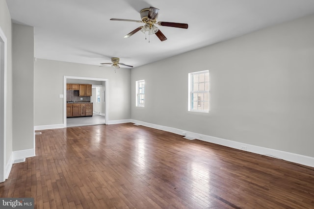 unfurnished room featuring a ceiling fan, dark wood finished floors, and baseboards