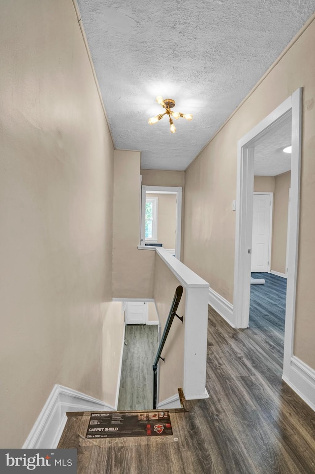 stairs featuring wood finished floors, baseboards, and a textured ceiling
