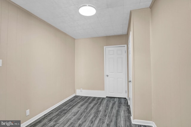 spare room with dark wood-style flooring and baseboards