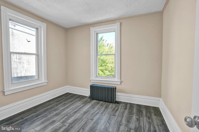 spare room featuring radiator, dark wood-style floors, a textured ceiling, and baseboards