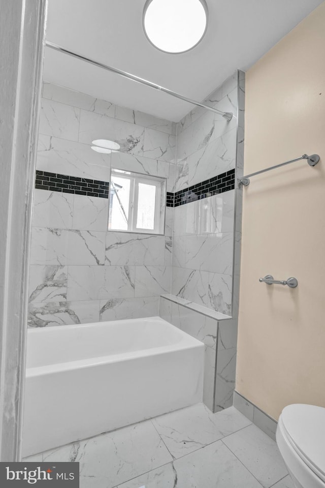 full bath with marble look tiles, toilet, and bathing tub / shower combination