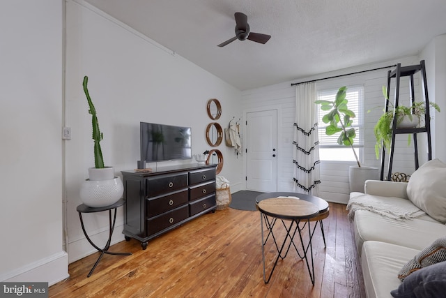 living room featuring light wood finished floors, a ceiling fan, and lofted ceiling