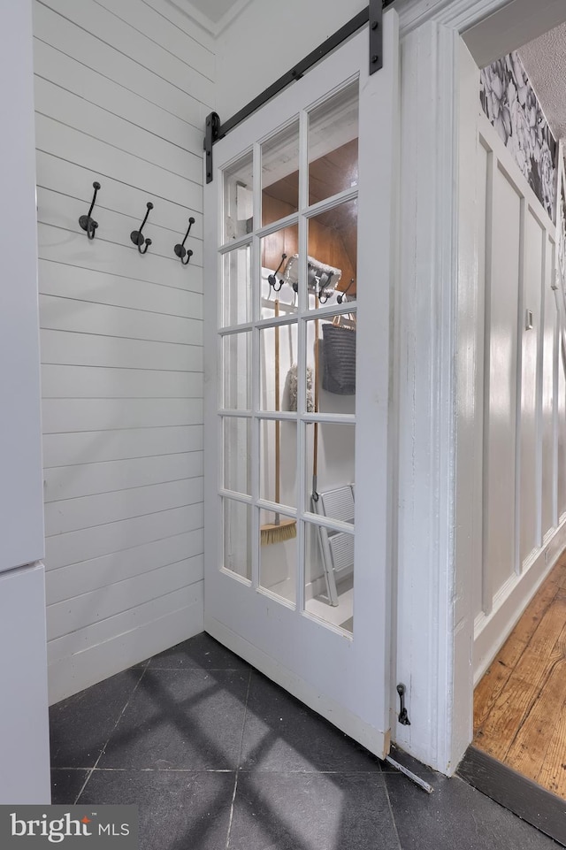 mudroom featuring a barn door and wood walls
