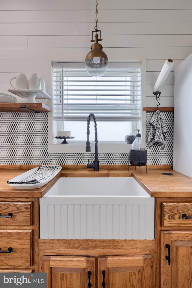 kitchen featuring a sink, tasteful backsplash, wood counters, and brown cabinets