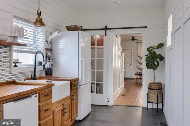 kitchen with wood counters, a barn door, crown molding, dark tile patterned floors, and healthy amount of natural light