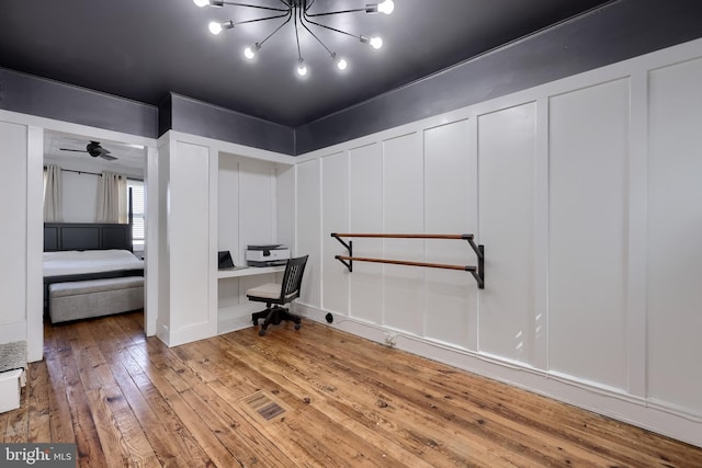 office area with a decorative wall, hardwood / wood-style floors, and a chandelier