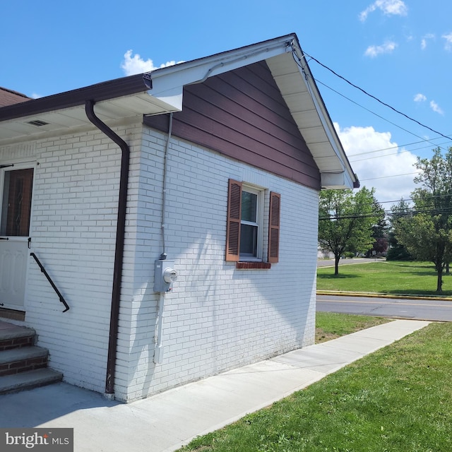view of home's exterior with brick siding and a lawn