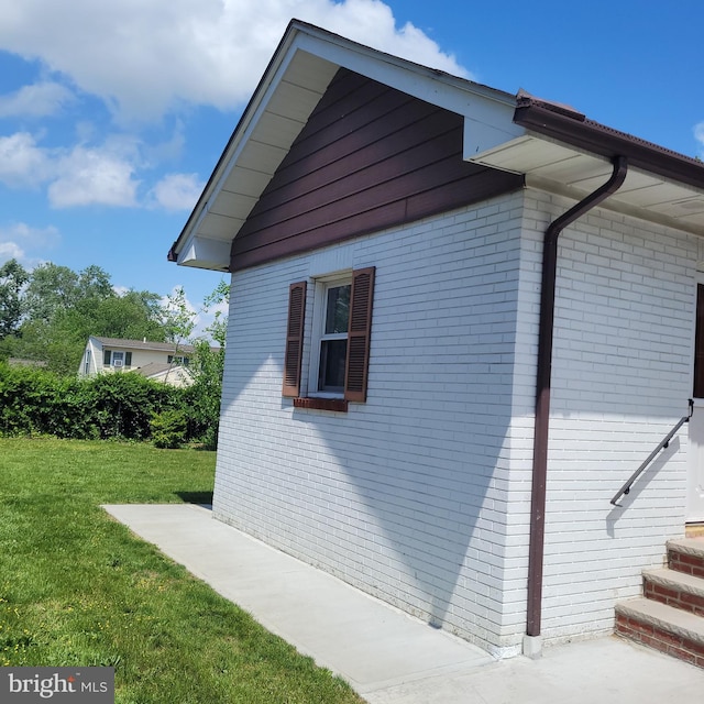 view of side of home featuring brick siding and a lawn