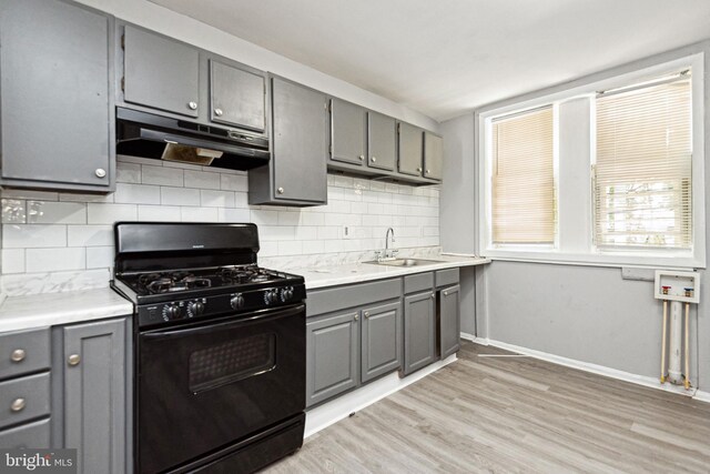 908 Mckean Ave, Baltimore, MD 21217 - kitchen featuring light wood-style flooring, a sink, black range with gas cooktop, under cabinet range hood, and gray cabinetry