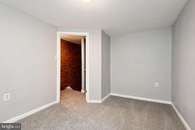 908 Mckean Ave, Baltimore, MD 21217 - unfurnished room featuring baseboards, brick wall, and carpet