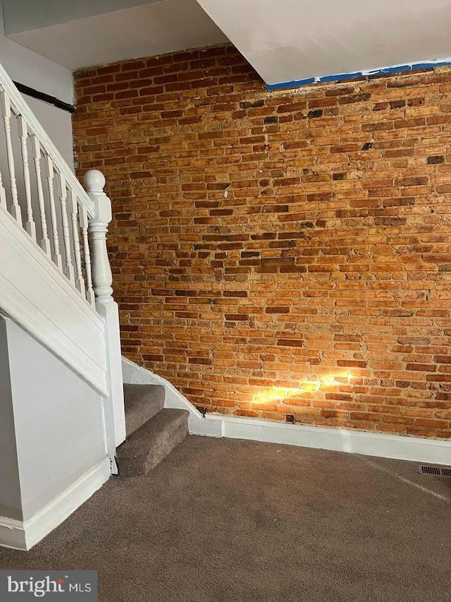 stairs with brick wall, carpet floors, baseboards, and visible vents
