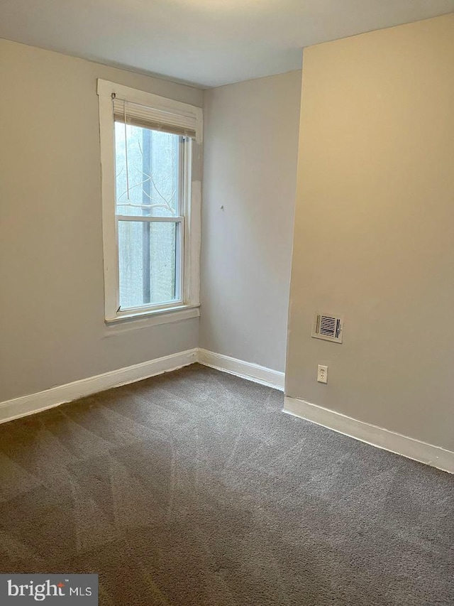 unfurnished room featuring baseboards and dark colored carpet