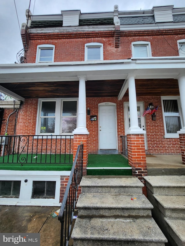 117 S Harrison St, Wilmington, DE 19805 - view of exterior entry with brick siding, mansard roof, and a porch