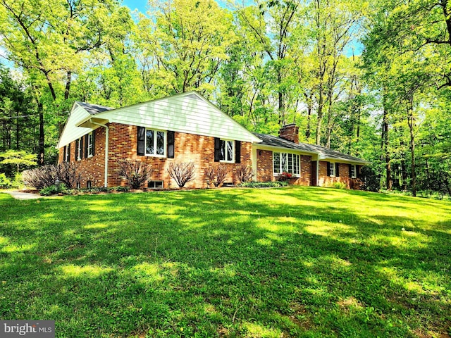view of front of property featuring a chimney, a front lawn, and brick siding