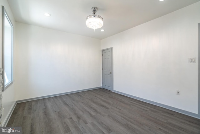 spare room with baseboards, an inviting chandelier, recessed lighting, and wood finished floors